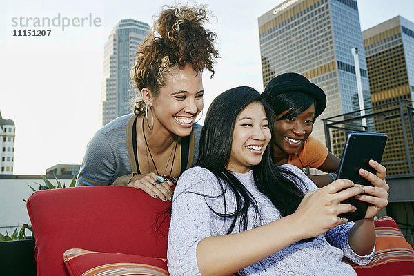 Frauen benutzen ein digitales Tablet auf einem städtischen Hausdach