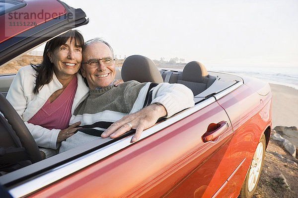Älteres Paar fährt Cabrio am Strand
