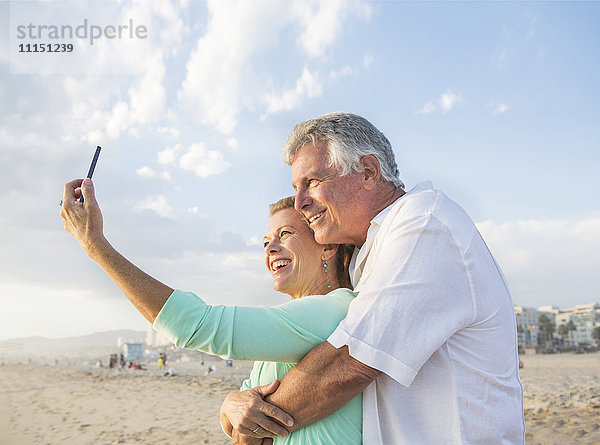Kaukasisches Paar macht Handy-Selfie am Strand