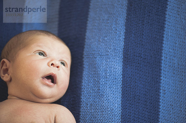 Nahaufnahme eines neugeborenen gemischtrassigen Babys  das auf einer gestreiften Decke liegt