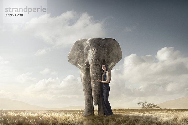 Frau umarmt Elefant in abgelegenem Feld