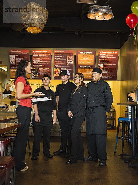 Hispanischer Geschäftsinhaber und Angestellte im Gespräch in einem Cafe