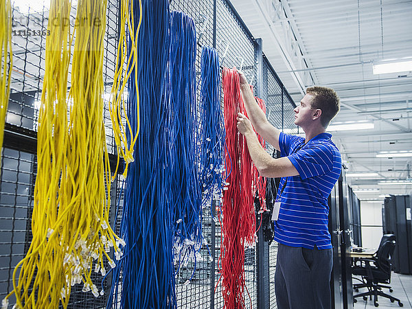 Kaukasischer Techniker hängt Kabel im Serverraum auf