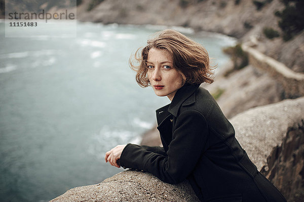 Kaukasische Frau steht auf einer Klippe über der Küste