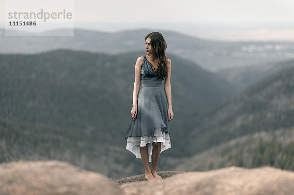 Kaukasische Frau steht auf einem abgelegenen Berggipfel