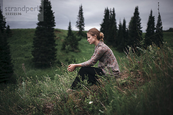 Kaukasische Frau sitzt in einem abgelegenen Feld