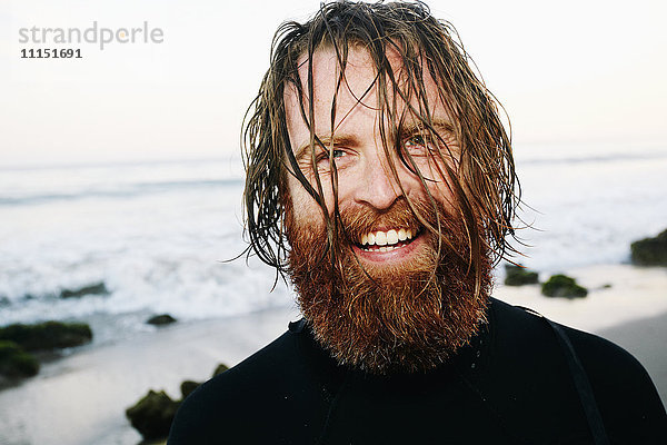 Kaukasischer Surfer mit nassen Haaren am Strand