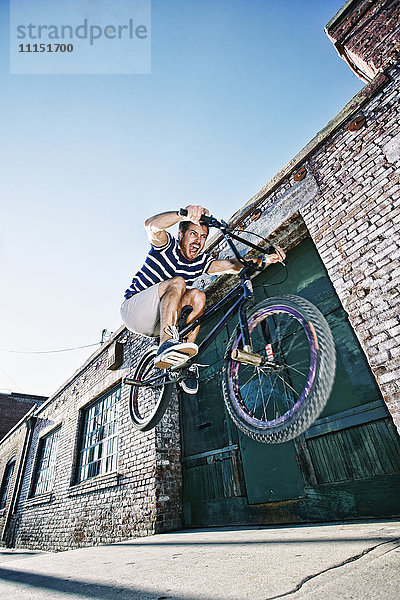 Kaukasischer Mann springt auf BMX-Rad