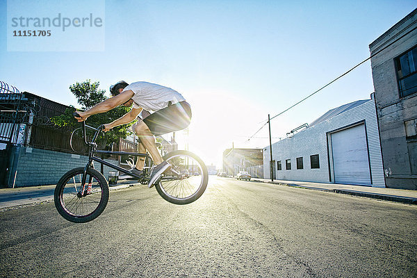 Kaukasischer Mann springt auf BMX-Rad auf der Straße