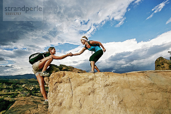 Frau hilft Freund klettern Felsformation
