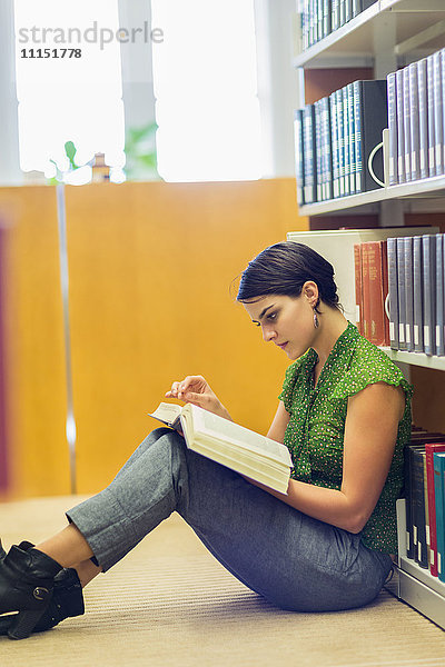 Gemischtrassiger Student liest ein Buch in der Bibliothek