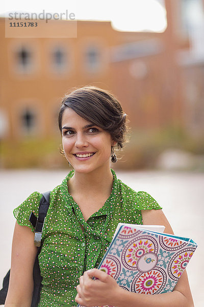 Gemischtrassiger Student trägt Bücher auf dem Campus