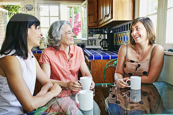 Kaukasische Mutter und Töchter trinken Kaffee in der Küche