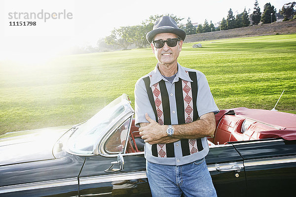 Gemischtrassiger Mann lächelt in der Nähe eines klassischen Cabriolets