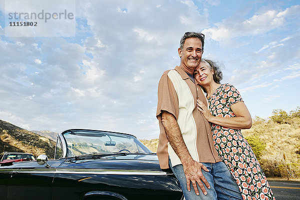Lächelndes Paar in der Nähe eines klassischen Cabriolets