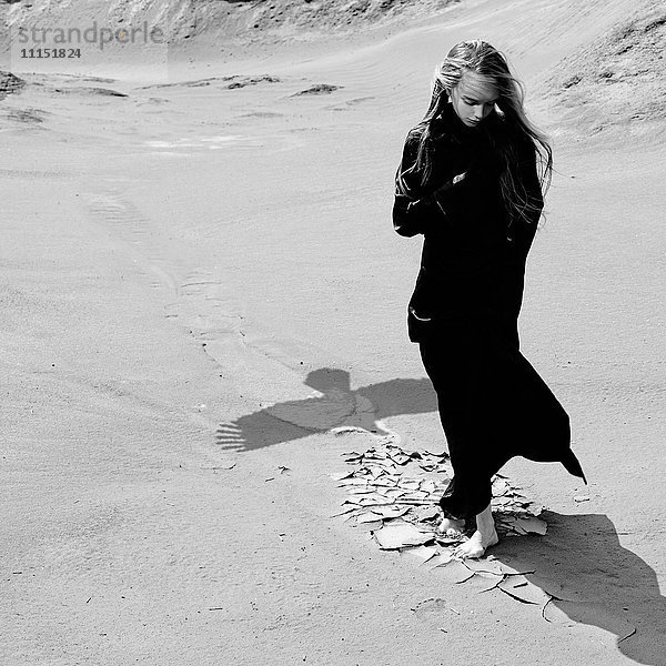 Kaukasisches Teenager-Mädchen steht am Strand in der Nähe des Schattens eines Adlers
