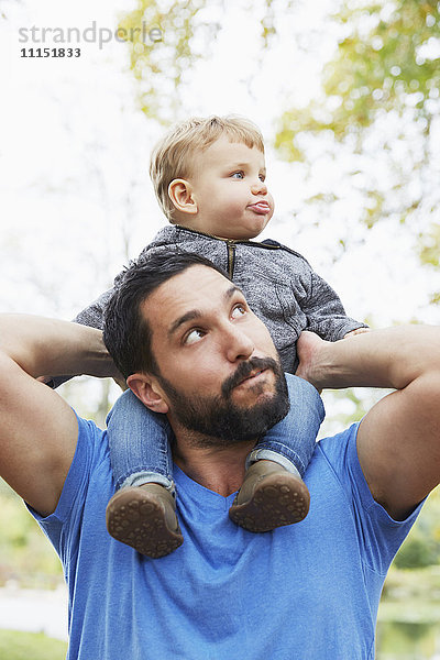 Kaukasischer Vater trägt seinen kleinen Sohn im Freien