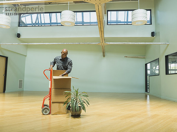 Schwarzer Geschäftsmann packt Kartons in leerem Büro aus