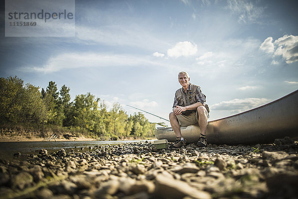 Älterer kaukasischer Mann sitzt im Kanu auf dem Flussbett