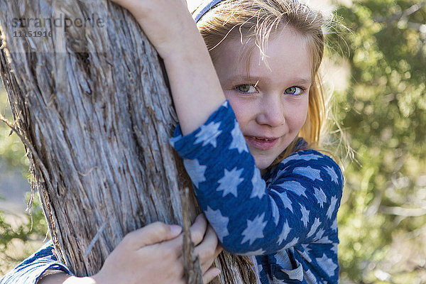 Kaukasisches Mädchen umarmt Baum im Freien