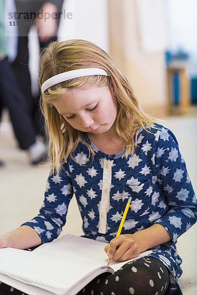 Kaukasisches Mädchen schreibt im Klassenzimmer