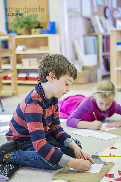 Kaukasische Kinder schreiben im Klassenzimmer