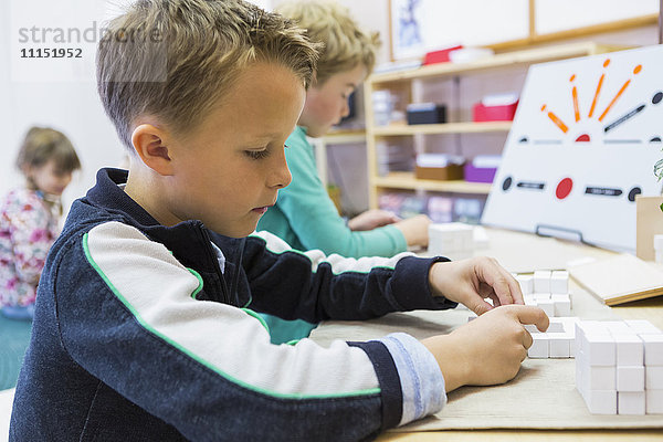 Nahaufnahme eines Jungen  der im Klassenzimmer ein Rätsel löst