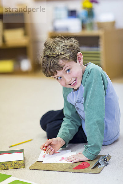 Lächelnder Junge beim Zeichnen im Klassenzimmer