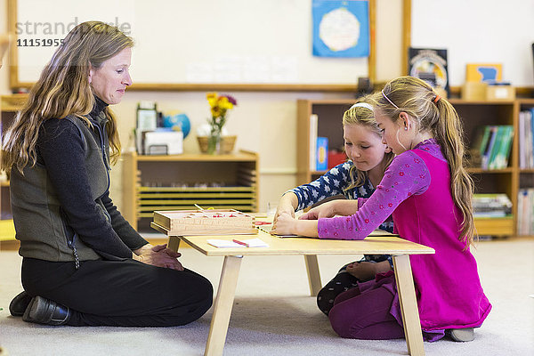 Montessori-Lehrer hilft Schülern im Klassenzimmer