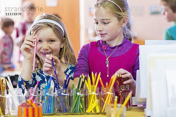 Kaukasische Mädchen wählen mehrfarbige Bleistifte im Klassenzimmer