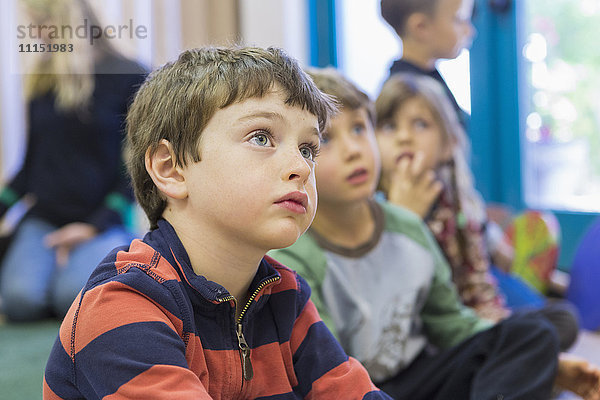 Kinder  die im Klassenzimmer sitzen und zuhören