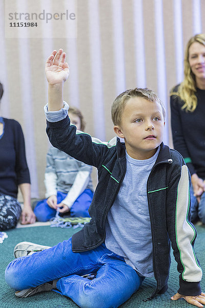 Junge hebt die Hand im Klassenzimmer