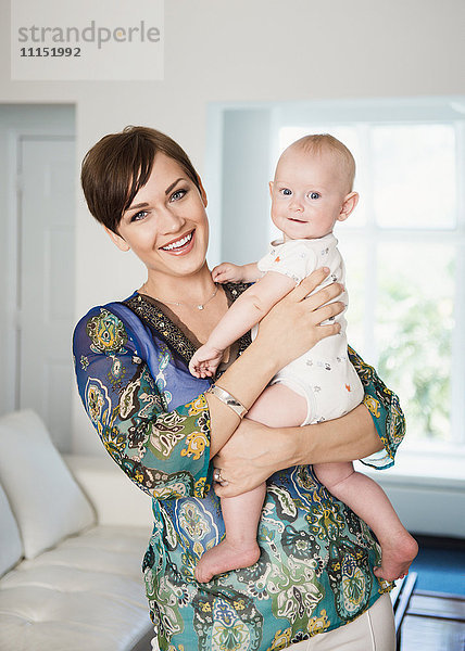 Kaukasische Mutter hält Baby im Wohnzimmer