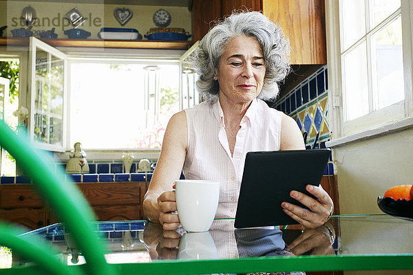 Kaukasische Frau benutzt digitales Tablet in der Küche