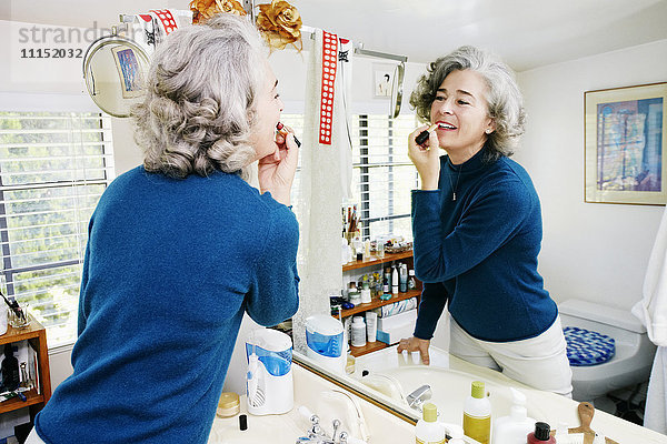 Kaukasische Frau trägt Make-up im Spiegel auf