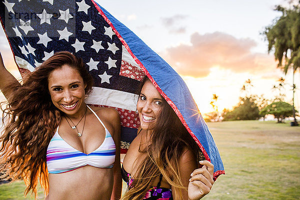 Frauen unter amerikanischer Flagge stehend bei Sonnenuntergang