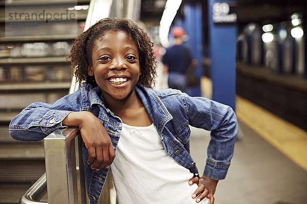 Lächelndes Mädchen lehnt an einer U-Bahn-Treppe