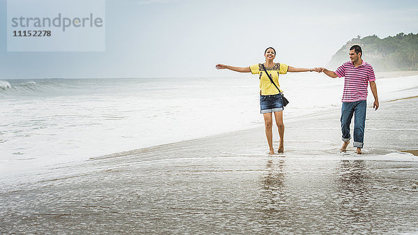 Hispanisches Paar spielt in den Wellen am Strand