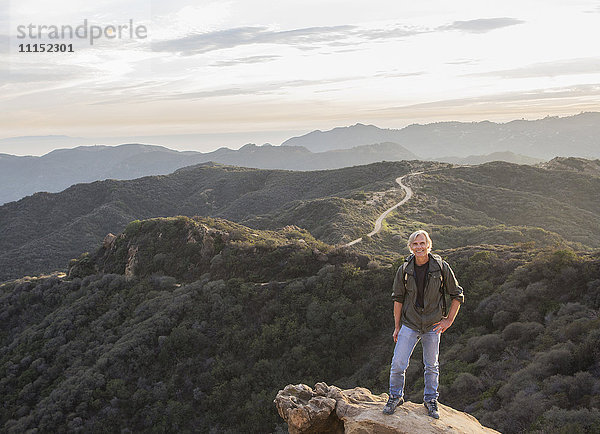 Älterer kaukasischer Mann auf felsiger Bergkuppe
