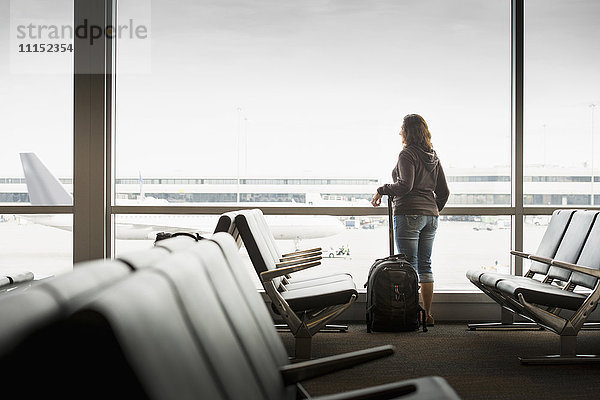 Hispanische Frau schaut aus dem Flughafenfenster