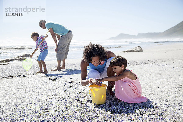 Gemischtrassige Familie spielt am Strand