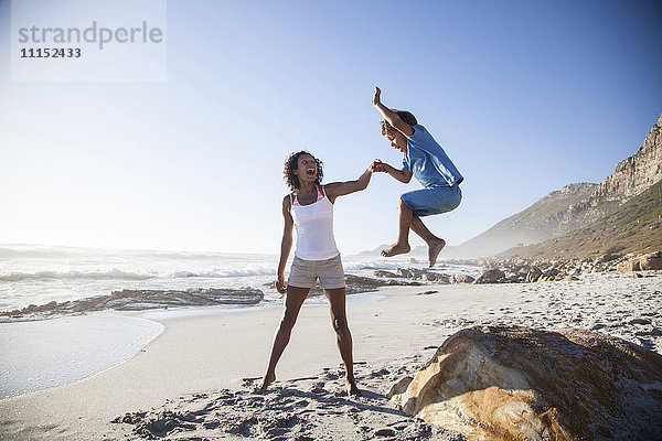 Gemischtrassige Mutter und Sohn spielen am Strand