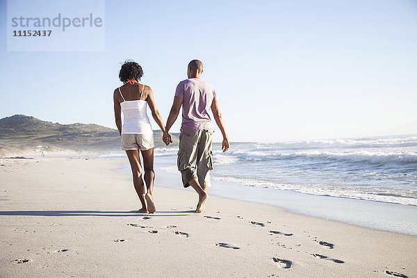 Gemischtrassiges Paar geht am Strand spazieren
