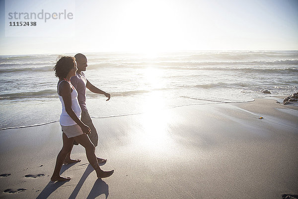 Gemischtrassiges Paar geht am Strand spazieren