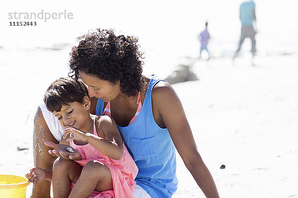Gemischtrassige Mutter und Tochter spielen am Strand