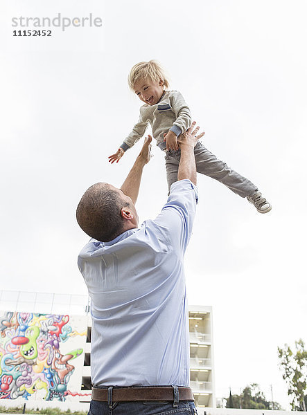 Hispanischer Vater wirft seinen Sohn im Freien in die Luft