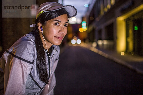 Asiatischer Läufer  der nachts auf einer Straße in der Stadt rastet
