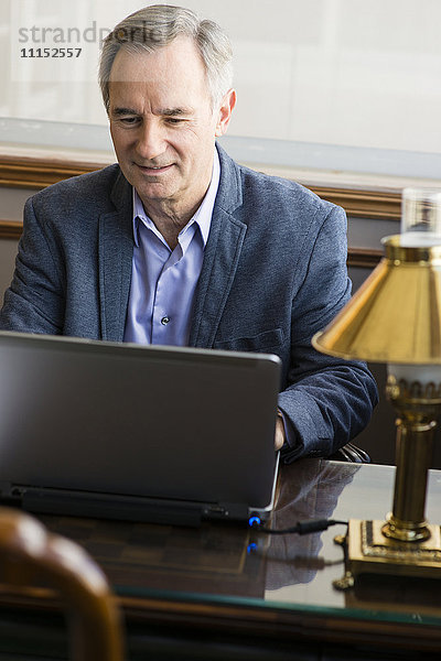 Kaukasischer Geschäftsmann arbeitet am Laptop am Schreibtisch