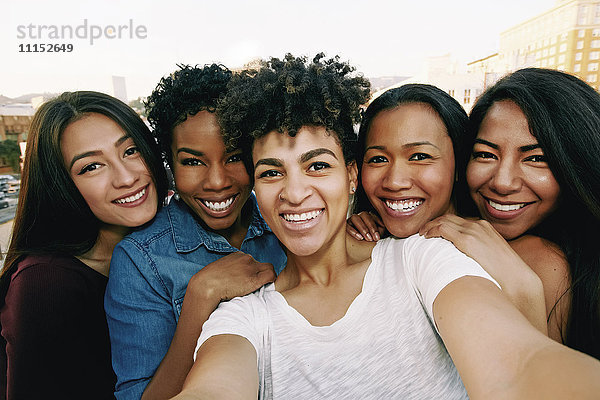 Lächelnde Frauen nehmen Selfie auf städtischen Dach