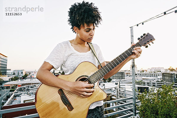 Gitarre spielende Frau auf einem Hausdach